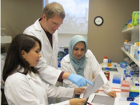 Holger Wille, co-principal investigator and an associate professor in the Department of Biochemistry at the University of Alberta's Faculty of Medicine and Dentistry, looks over electron micrographs with other researchers at the University of Alberta.