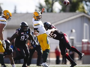 Edmonton Eskimos quaterback Mike Reilly, centre, gets rid of the ball as Calgary Stampeders' Micah Johnson , left, and Ja'Gared Davis during second half CFL football action in Calgary, Monday, Sept. 5, 2016.