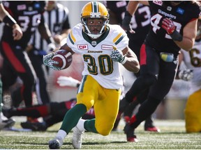 Edmonton Eskimos' John White (30) runs as Calgary Stampeders' players apply pressure during second half CFL football action in Calgary, Monday, Sept. 5, 2016.