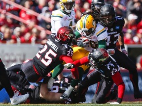 Edmonton Eskimos' Kenzel Doe, centre, is brought down by Calgary Stampeders' players during first half CFL football action in Calgary, Monday, Sept. 5, 2016.