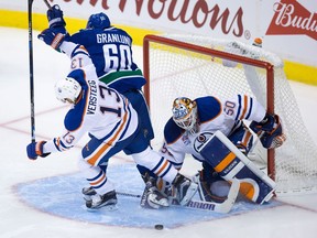 Edmonton Oilers' goalie Jonas Gustavsson, right, of Sweden, stops Vancouver Canucks' Markus Granlund, of Finland, (60) as he's checked by Oilers' Kris Versteeg during the second period of a pre-season NHL hockey game in Vancouver, B.C., on Wednesday September 28, 2016.