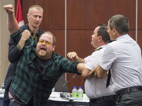Security guards try to restrain a demonstrator from interrupting the National Energy Board public hearing into the proposed $15.7-billion Energy East pipeline project proposed by TransCanada on Aug. 29, 2016 in Montreal.