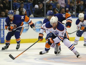 Edmonton Oilers' Taylor Hall (4) and New York Islanders' Kyle Okposo (21) chase the puck down ice as Islanders' Thomas Hickey (14) follows at left in the first period of an NHL hockey game on Thursday, Oct. 17, 2013, in Uniondale, N.Y. Hall scored two goals for the Oilers and Okposo scored a goal during the Islanders 3-2 win.