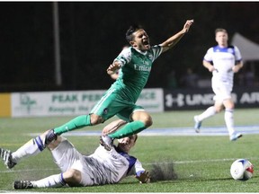 FC Edmonton captain Albert Watson trips New York Cosmos midfielder Andres Flores in a North American Soccer League game Saturday in Hempstead, NY. The game finished in a scoreless tie.