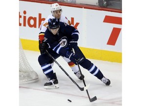 Winnipeg Jets' Jacob Trouba (8) carries the puck end in front of Calgary Flames' Mason Raymond (21) during first period NHL hockey action in Winnipeg, Sunday, October 19, 2014.
