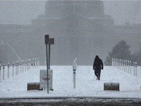 A lonely figure makes their way past the Legislature as the snow continues to fall in Edmonton Friday, October 14, 2016.