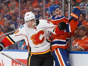 Brandon Davidson #88 of the Edmonton Oilers is taken to the boards by Matthew Tkachuk #19 of the Calgary Flames on October 12, 2016 at Rogers Place in Edmonton.