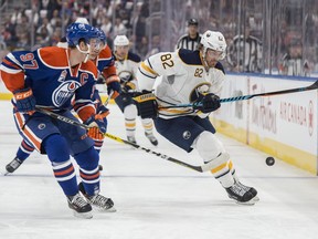 Connor McDavid (97) of the Edmonton Oilers watches the loose puck with Marcus Foligno of the Buffalo Sabres at Rogers Place in Edmonton on Sunday, Oct. 16, 2016.