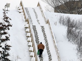 A man walks up a river valley staircase through a heavy snowfall in Edmonton.