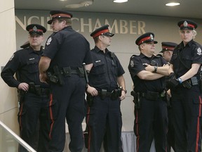 Police and security guards stand outside Edmonton City Council Chambers to prevent angry Edmonton taxi drivers from entering into Edmonton City Council Chambers where city council was having a meeting on the Uber taxi dispute on January 26, 2016.