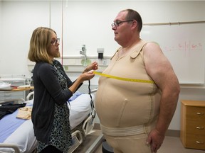 Marty Enokson gets measured by clinical bariatric consultant Katelyn Teske while he shows his custom supportive garment.