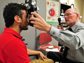 Clinical optometrist Dr. Greg King uses a phoropter on patient Nestor Ortiz at the Edmonton Mennonite Centre for Newcomers while providing eye exams to clients in 2014.