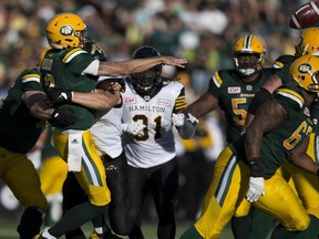 Edmonton Eskimos Mike Reilly (13) is hit on a throw by members of Hamilton Tiger-Cats during second half action at Commonwealth Stadium on Saturday, July 23, 2016 in Edmonton. Greg Southam / Postmedia Photos for various stories, columns (Gerry Moddejonge, terry Jones, Dan Barnes) running in Sunday, July 24 edition.