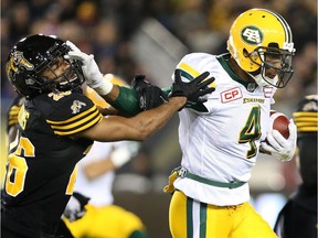 Edmonton Eskimos slotback Adarius Bowman (4) fends off Hamilton Tiger-Cats defensive back Johnny Adams (26)during the first-half of CFL football action in Hamilton on Friday, October 28, 2016.