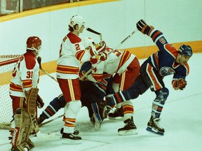 Edmonton Oilers winger Glenn Anderson, right, mixes it up in front of the Calgary Flames net, being guarded by goalie Mike Vernon, left, and defencemen Al MacInnis (#2) and Jamie Macoun (#34), during NHL action at the Saddledome on April 22, 1986.