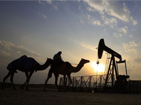 In this 2015 file photo, a man rides a camel through the desert oil field and winter camping area of Sakhir, Bahrain. OPEC nations have agreed in theory that they need to reduce their production to help boost global oil prices during a meeting in Algeria, but a major disagreement between regional rivals Saudi Arabia and Iran still may derail any cut.