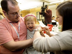 Ella Sikora, 4, sits on her dad's lap, Dr. Christopher Sikora, as she receives a flu shot from a nurse at the East Edmonton Public Health Centre, 7910 - 112 Ave., in Edmonton on Monday Oct. 24, 2016.