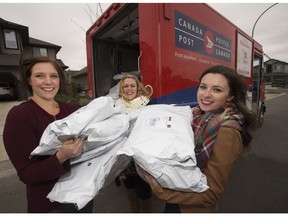 From left, Frock Box co-owners Jeanie Borremans, Shanlyn Cunningham and Jenna Hill pose for a photo as they load a mail truck with outgoing orders.