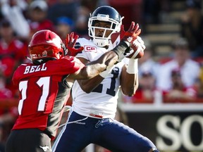 Toronto Argonauts' Vidal Hazelton makes a catch as Calgary Stampeders' Joshua Bell looks on during first quarter CFL football action in Calgary, Monday, July 13, 2015.