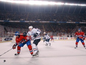 In this November 22, 2013 photo from the original Edmonton vs Montreal Heritage Classic at Commonwealth Stadium, Oilers Brad Isbister and Canadiens Craig Rivet battle over the puck.