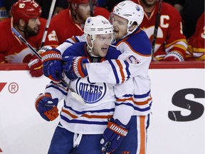 Edmonton Oilers' Mark Letestu, left, celebrates his game winning goal with Anton Lander in front of the Calgary Flames' bench during third period NHL action in Calgary, Alta., Friday Oct. 14, 2016.