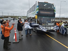 Workers hold a banner as a bus, carrying dignitaries, slices through during a celebration held on the North Saskatchewan River Bridge to mark the grand opening of Northeast Anthony Henday Drive.