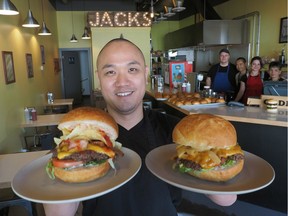 Jack's Burger Shack co-owner Tu Le holds a BBQ Crunch burger (left) and a Daily Special burger (right) at his restaurant in St. Albert.