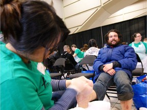 Kristian Antonio Patterson receives foot care from Pauline Luong at the Homeless Connect event at the Shaw Conference Centre on Sunday.