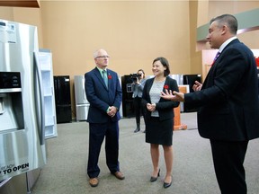 David Dodge, chairperson of Energy Efficiency Alberta, left, and Alberta Environment Minister Shannon Phillips  receive tips on buying a power-smart refrigerator from Trail Appliances director of sales Michael Seens.