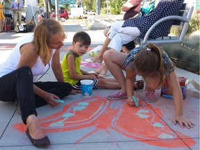 Artist Agnieszka Matejko leads two children in a chalk drawing at the scaled-back public market, which operated on Stony Plain Road every Friday this summer.