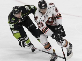 Edmonton Oil Kings forward Davis Koch, left and Calgary Hitmen defenceman Aaron Hyman reach for a puck during the first period of their WHL game at Rogers Place in Edmonton, Alberta on Friday, October 28, 2016.