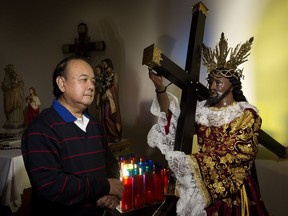 Lito Reyes poses with a statue of Jesus Christ, the Black Nazarene, at St. Anthony Church.