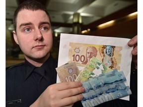 Const. Zachary Jansen holds up counterfeit  and altered currency as police have charged three suspects in relation to counterfeit money and warn retailers and consumers to be aware and how to spot a fake ones in Edmonton, Friday, November 25, 2016.