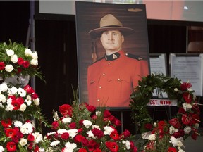 A photo of slain RCMP Constable David Wynn stands amongst flowers during his funeral procession in St. Albert, Alta., on Monday, January 26, 2015. Wynn died four days after he and Auxiliary Constable Derek Bond were shot by Shawn Rehn in St. Albert, Alta, on Saturday January 17, 2015.