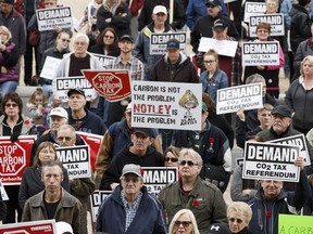 Demonstrators hold anti-carbon tax signs during a rally held at the Alberta Legislature in Edmonton, on November 5, 2016.