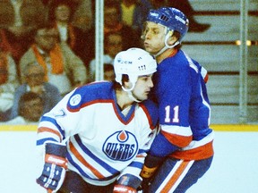 Edmonton Oilers defenceman Paul Coffey, left, tangles with new York Islanders centre Wayne Merrick during the 1982-83 NHL season.