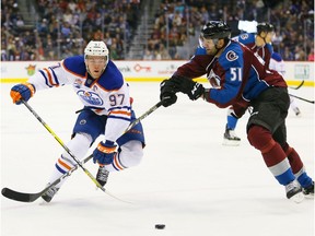 Connor McDavid #97 of the Edmonton Oilers skates with the puck around Fedor Tyutin #51 of the Colorado Avalanche during the first period at Pepsi Center on November 23, 2016 in Denver, Colorado.