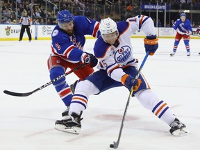 NEW YORK, NY - NOVEMBER 03: Tyler Pitlick #15 of the Edmonton Oilers moves around Kevin Klein #8 of the New York Rangers during the first period at Madison Square Garden on November 3, 2016 in New York City.