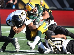 Edmonton Eskimos' John White (30) is tackled by Hamilton Tiger-Cats defensive back Mike Daly (35) during the first-half of CFL eastern semi-final football action, in Hamilton, Ont., on Sunday, November 13, 2016.