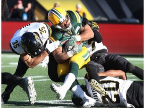 Edmonton Eskimos' John White (30) is tackled by Hamilton Tiger-Cats defensive back Mike Daly (35) during the first-half of CFL eastern semi-final football action, in Hamilton, Ont., on Sunday, November 13, 2016.