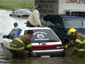 Noel Dery sits on top of his Mazda 323 while firefighters push his car out of the water during a flash flood in 2004. Epcor says it can save 10 per cent on Edmonton's stormwater and other capital projects.