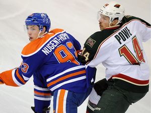 Edmonton Oilers centre Ryan Nugent-Hopkins (left) is checked by Minnesota Wild center Darroll Powe (right) during NHL action at Rexall Place on Nov. 30, 2011.