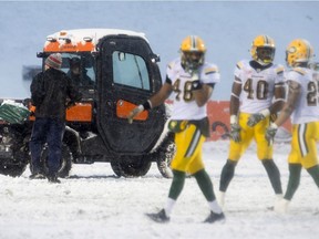 Grounds crew clear snow from the lines as Edmonton Eskimos players move into position on the field during the CFL Eastern Final action, in Ottawa on Sunday, November 20, 2016.