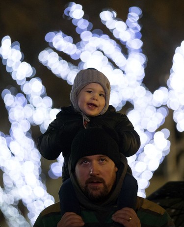 Leland Moore, 2, sits on his dad Eric Moore's shoulders as the two watch the Holiday Light Up ceremonies in Churchill Square, in Edmonton on Saturday Nov. 12, 2016.