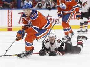 Arizona Coyotes' Laurent Dauphin (76) tries to get the puck from Edmonton Oilers' Matthew Benning (83) during first period NHL action in Edmonton, Alta., on Sunday November 27, 2016.