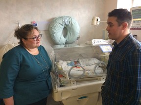 Health Minister Sarah Hoffman, left, speaks with Quinn Kennedy about his five-day-old son Brooks in the neonatal intensive care unit at the Misericordia Hospital on Tuesday.