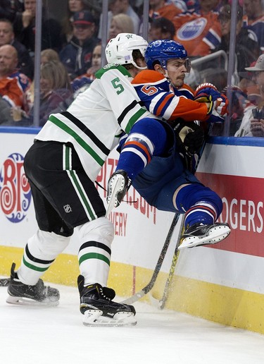 The Edmonton Oilers' Anton Lander (51) is checked into the boards by the Dallas Stars' Jamie Oleksiak (5) during second period NHL action at Rogers Place, in Edmonton on Friday Nov. 10, 2016.