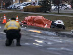 An Edmonton Police Service officer takes photographs as officers investigate a fatal collision on 97 Street at 160 Avenue in Edmonton, Alberta on Monday, Oct. 24, 2016. Six people were recognized Wednesday at an Edmonton Police Commission meeting for the roles they played in trying to save a woman at the fiery scene.