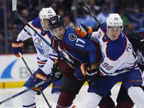 Colorado Avalanche right wing Rene Bourque, center, fights while pursuing the puck with Edmonton Oilers right wing Jesse Puljujarvi, right, of Sweden, and Edmonton Oilers left wing Milan Lucic in the first period of an NHL hockey game, Wednesday, Nov. 23, 2016, in Denver.