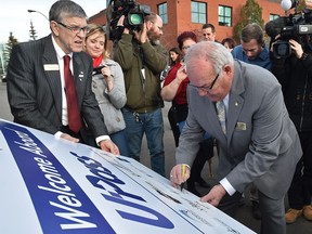 Spruce Grove Mayor Bill Kesanko signs a welcome aboard sign attached to an ETS bus at a celebration welcoming the three newest cities of Fort Saskatchewan, Leduc and Spruce Grove to the U-Pass program, in Edmonton, Thursday, Nov. 24, 2016.
